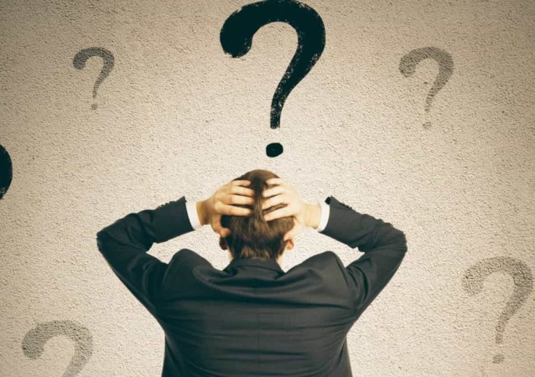 Back of a business person surrounded with lots of Question Marks